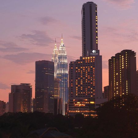 Doubletree By Hilton Kuala Lumpur Interior foto The photo showcases a city skyline at dusk, featuring tall buildings against a colorful sunset. Prominent in the image are two tower-like structures, which appear to be twin skyscrapers illuminated in a striking way, suggesting they might be iconic l