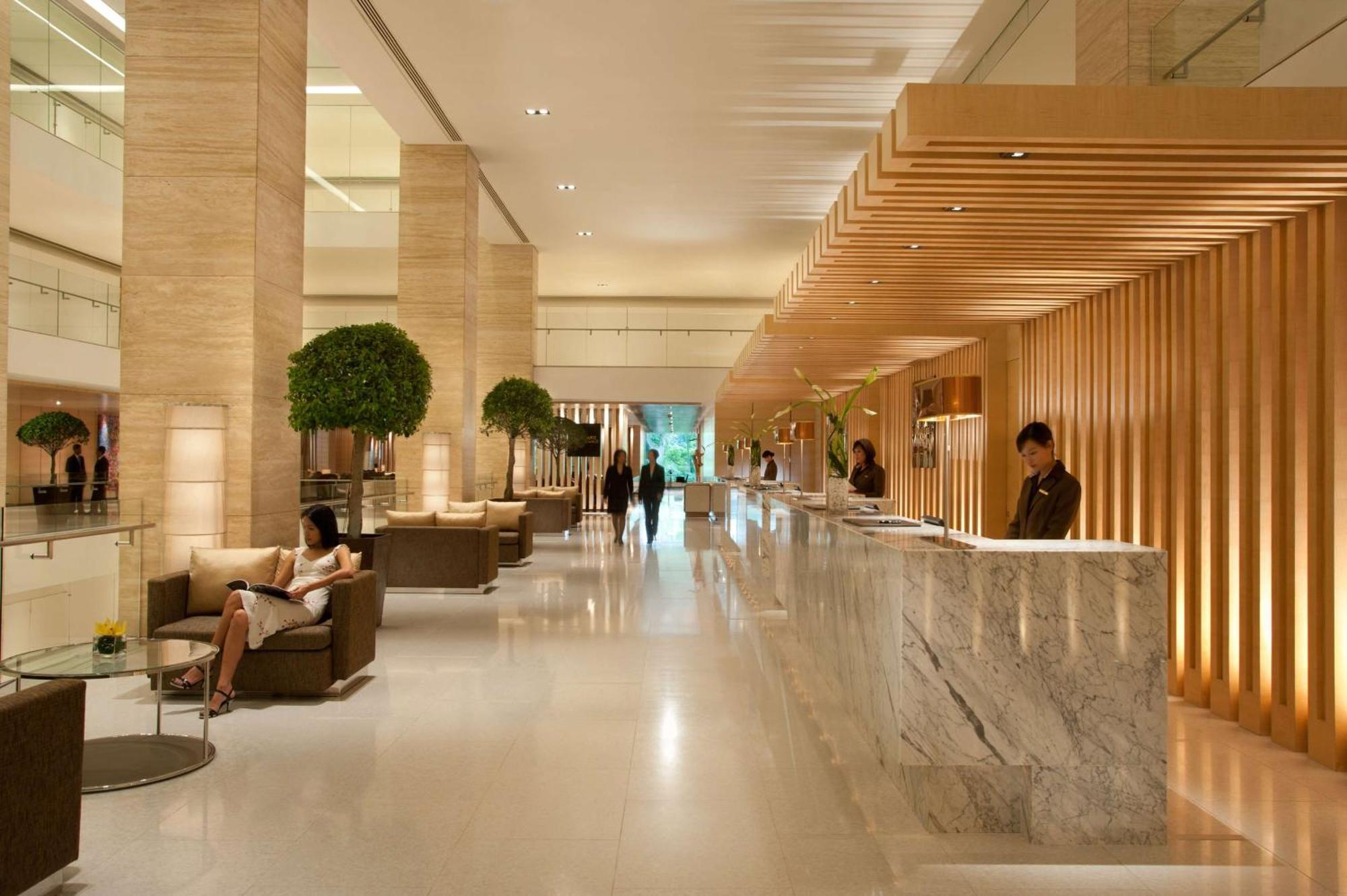 Doubletree By Hilton Kuala Lumpur Exterior foto The photo shows a modern hotel lobby. It features a spacious, well-lit area with high ceilings and elegant design elements. The reception desk, made of marble, is positioned prominently, with staff members attending to guests. There are several comfo