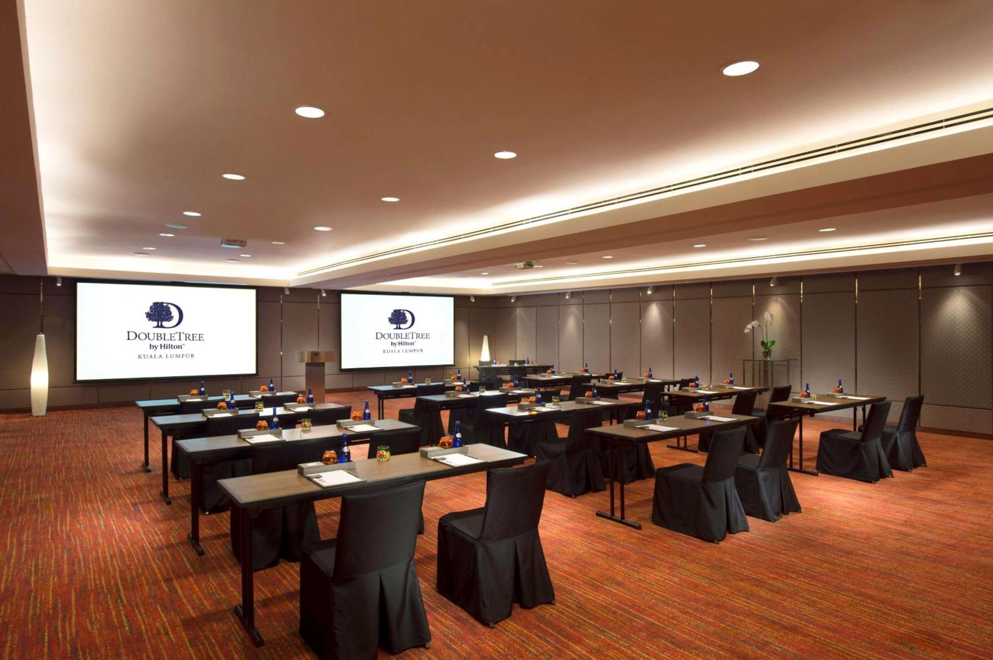 Doubletree By Hilton Kuala Lumpur Exterior foto The image shows a conference or meeting room setup. There are several rows of tables arranged for participants, each covered with a black tablecloth. The tables are equipped with stationery, suggesting that the space is intended for a professional ga